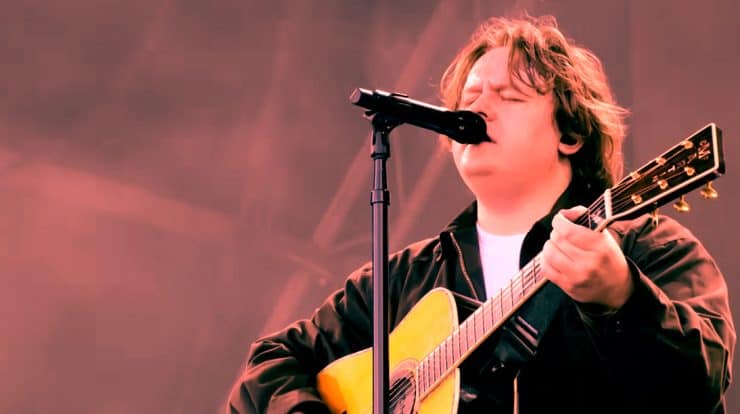 A young musician passionately singing and playing acoustic guitar at a live performance, capturing the essence of indie and singer-songwriter music genres.