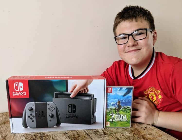 Teenage boy smiling at the camera with a Nintendo Switch