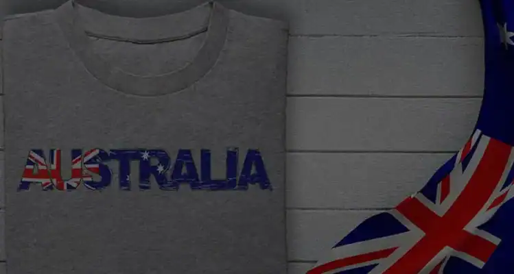 Grey folded T-shirt with “AUSTRALIA” artwork in flag colours beside fabric with Australian flag detail—Australian owned custom apparel from T Shirts Australia.