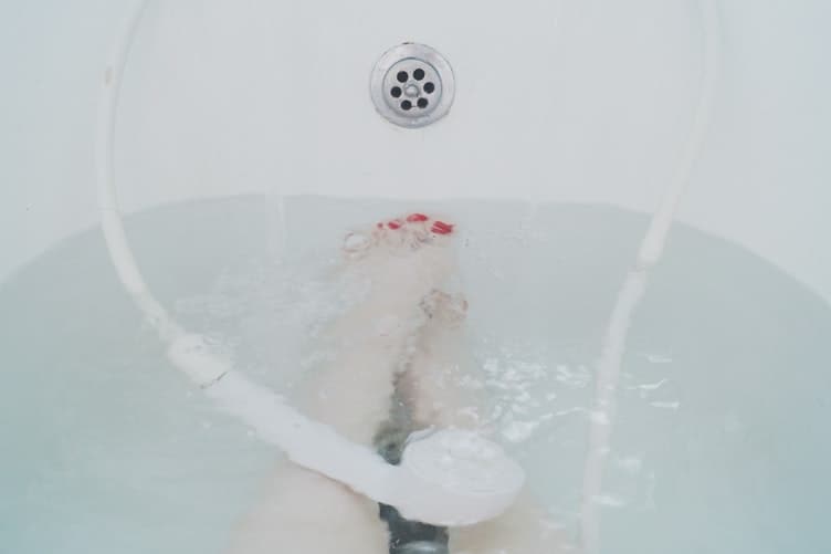 A shower head submerged in water in a bath