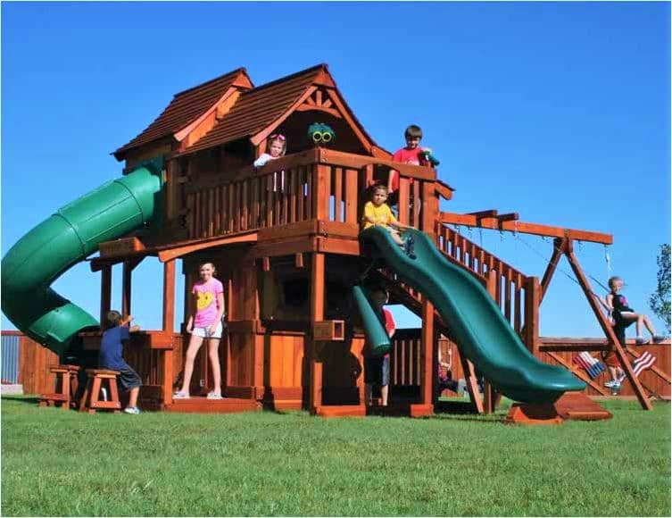 Children playing on a massive Backyard Fun Factory Maverick tri-level, upper cabin, lookout shack, fun deck, lower cabin, lower porch, boardwalk, twister and rave slide, punching bag, lemonade stand with sturdy swing beam. This shows how Yes, investing in a backyard playset a smart choice!
