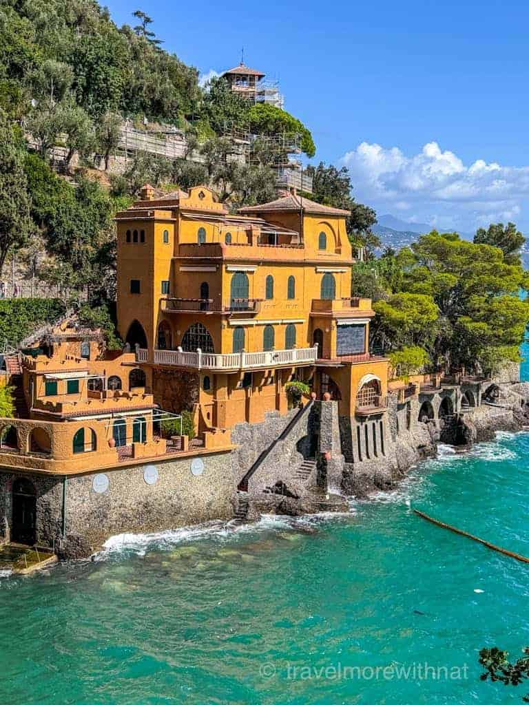 Multi-level, terracotta-coloured villa built into a hillside overlooking turquoise coastal waters. This is the stunning view from Portofino viewpoint.