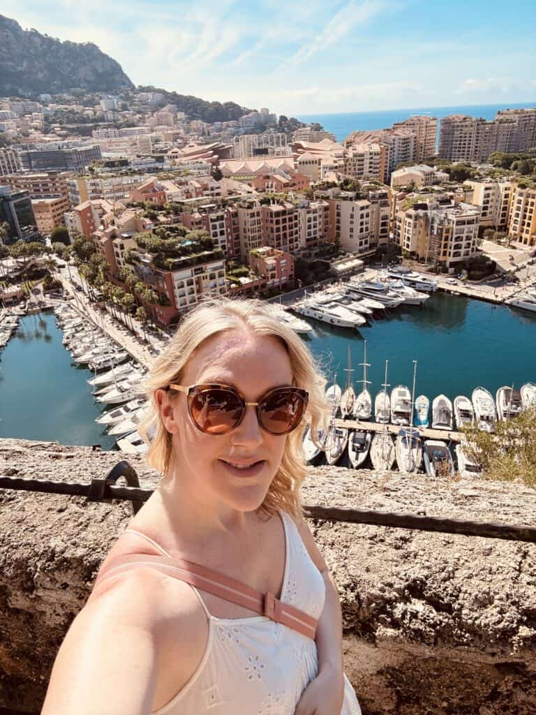 Woman posing above the yacht-filled harbour of and coastal city of Monaco, linked to what to see in Menton.