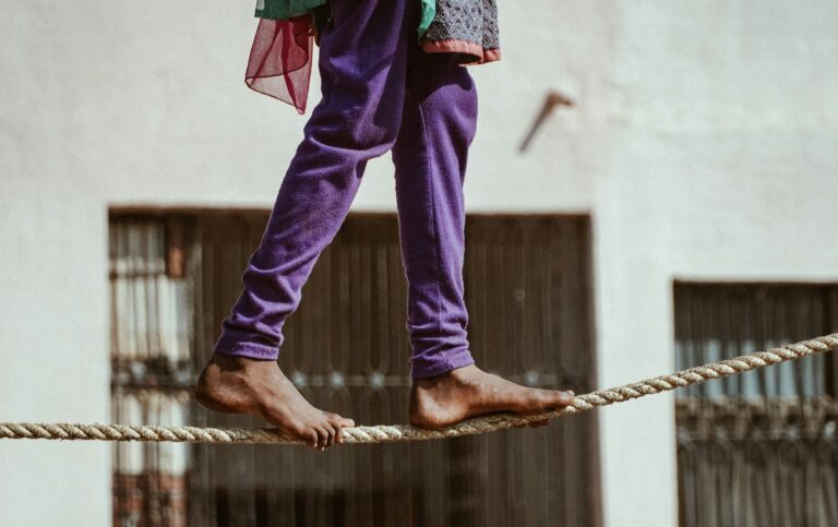 “Barefoot person walking a tightrope, symbolising dynamic balance and focus
