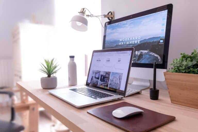 Skapar passiva inkomster med en Macbook pro på ett bord bredvid en vit Imac och en datormus.