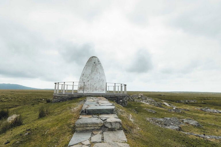 Stone monument on a grassy Irish landscape with cloudy sky, travel Ireland Today, scenic Irish sightseeing destination, historic monument in Ireland.