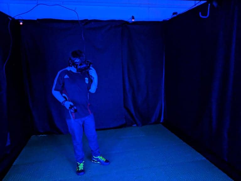 Ben inside a black booth, wearing a VR headset and holding a hand set.