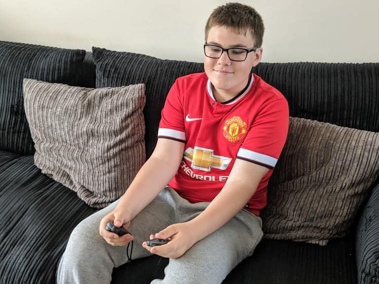 A teenage boy sitting on a sofa playing a Nintendo Switch