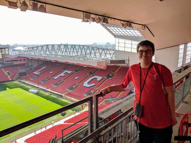 A teenage boy standing in Anfield stadium