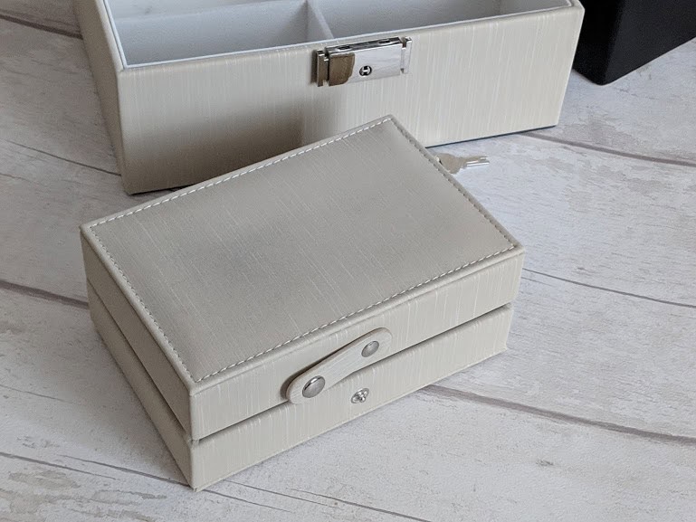 a closed jewellery box on a table top, next to a larger white jewellery box