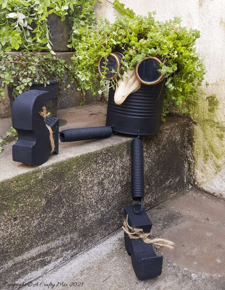 Looking for a creative way to repurpose a tin can? The you'll love this tin can steampunk planter. We call him Dr Edinose and he's sure to add a little whimsy to your outdoor decor. #steampunkplanter #ACraftyMix #TinCanRecycle