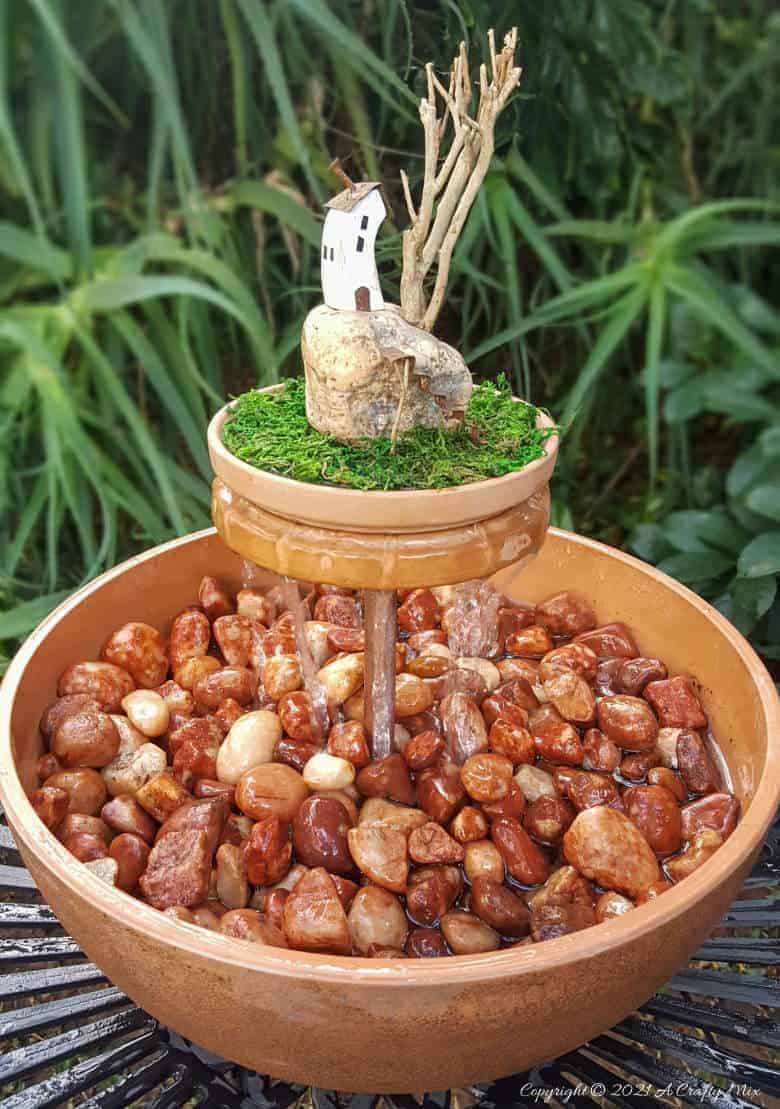 This photo-rich tutorial will show you how just how easy it is to repurpose an empty CD case and turn it in a CD spindle water feature bringing a calming, zen-like decorative feel to any space. #Spindlerepurpose #ACraftyMix #waterfeature