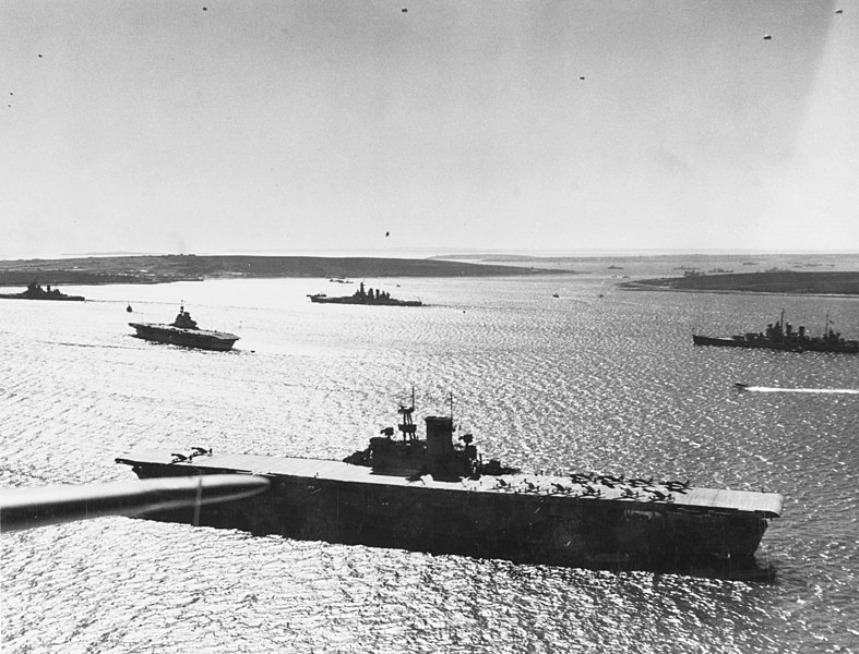 USS Wasp ligt voor anker in Scapa Flow in april 1942, met meerdere geallieerde oorlogsschepen op de achtergrond.
