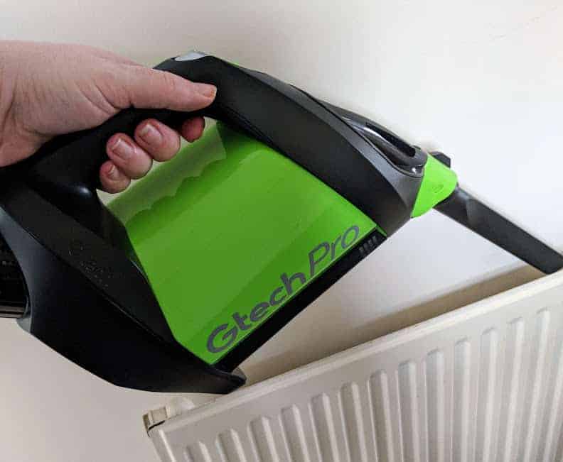 A green Gtech Pro hoovering a radiator