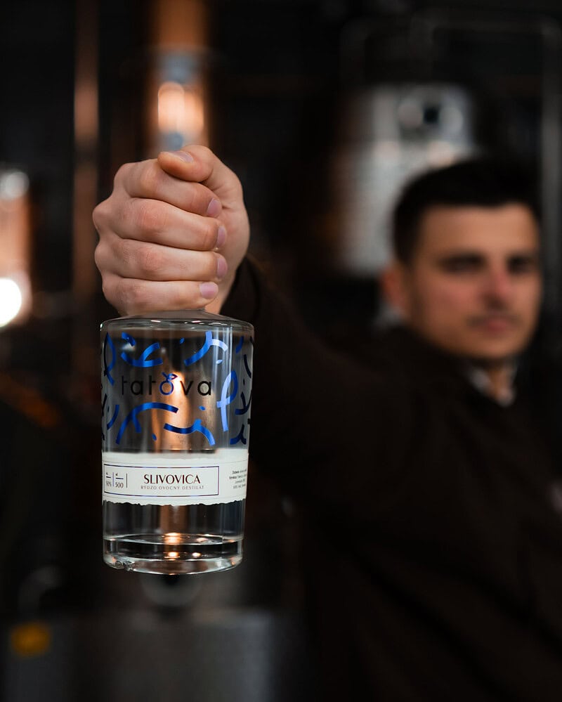 barman drziaci lahev slivovice tatova z lokalnych sliviek s obsahom alkoholu 50%, objem 0,5L