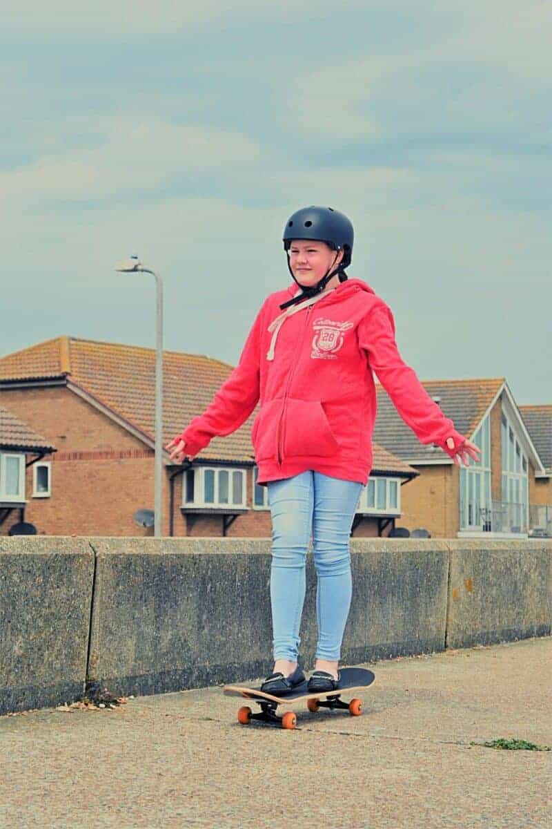 teenage girl skateboarding on concrete on the beach front.