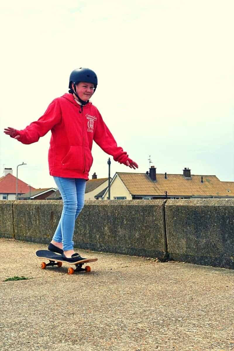 teenage girl skateboarding on concrete on the beach front.