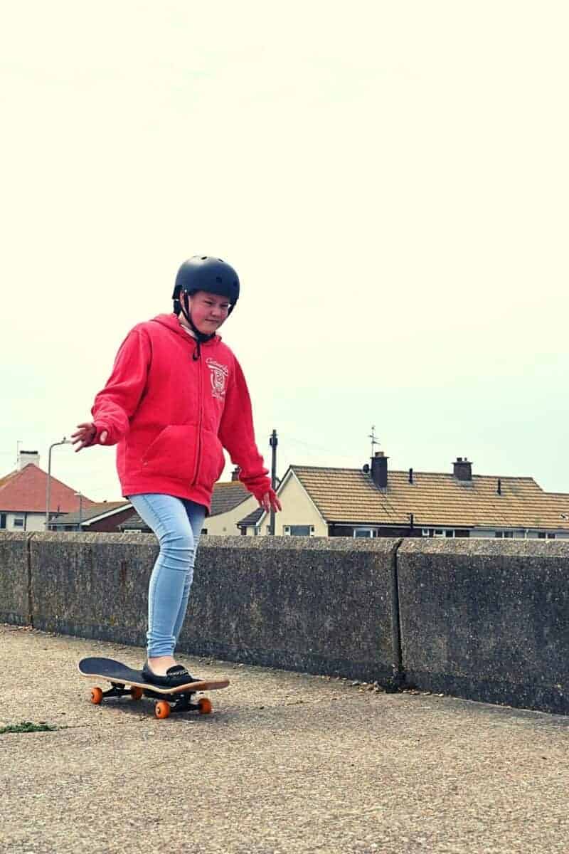 teenage girl skateboarding on concrete on the beach front.