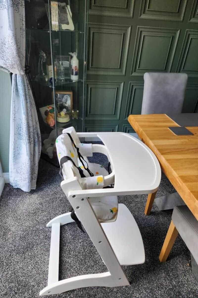 highchair with tray next to a dining table.