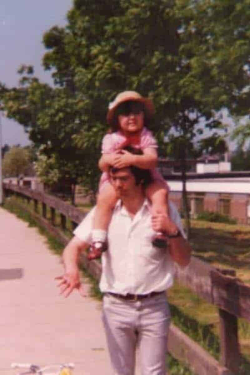 A little girl sat on her father's shoulders whilst outside
