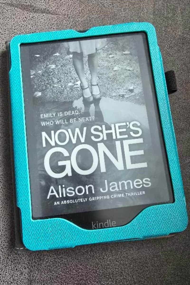 A Kindle e-reader in a turquoise case displays the cover of "Now She’s Gone" by Alison James, perfect for a Midweek Catch-Up, featuring a black-and-white image of a girl in a dress standing on a path.