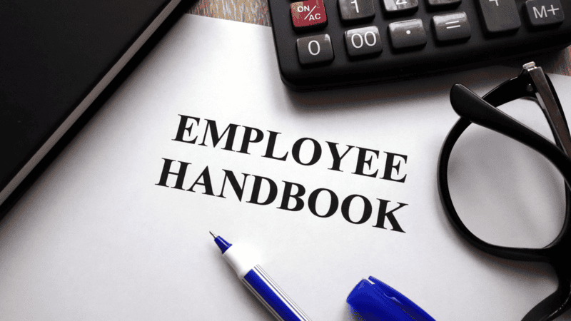 employee handbook typed out on a document and placed on a desk.