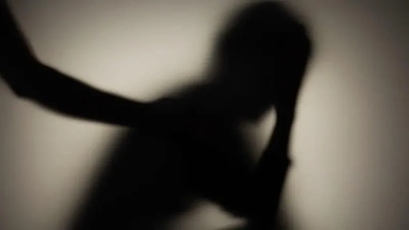 A shadowy figure sits in the background with head in hand as another figure reaches out to pat their back.