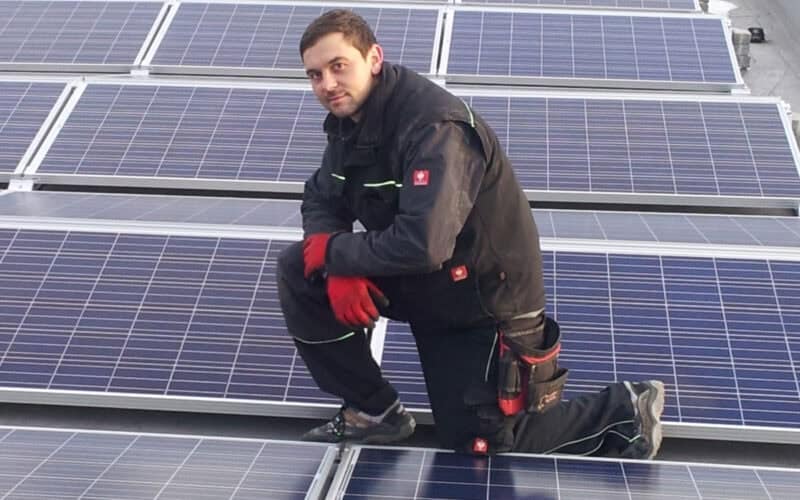 Solaranlagen-Installateur bei der Montage von PV-Modulen auf einem Dach, Fachmann für Solarenergie, nachhaltige Energieversorgung, Kili Solar-Systeme, umweltfreundliche Stromerzeugung.