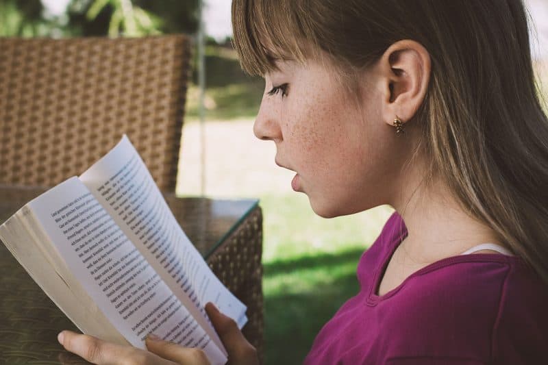 Niña leyendo en jardín
