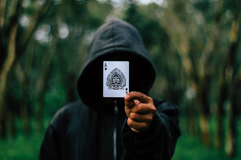 Persona encapuchada muestra un as de picas