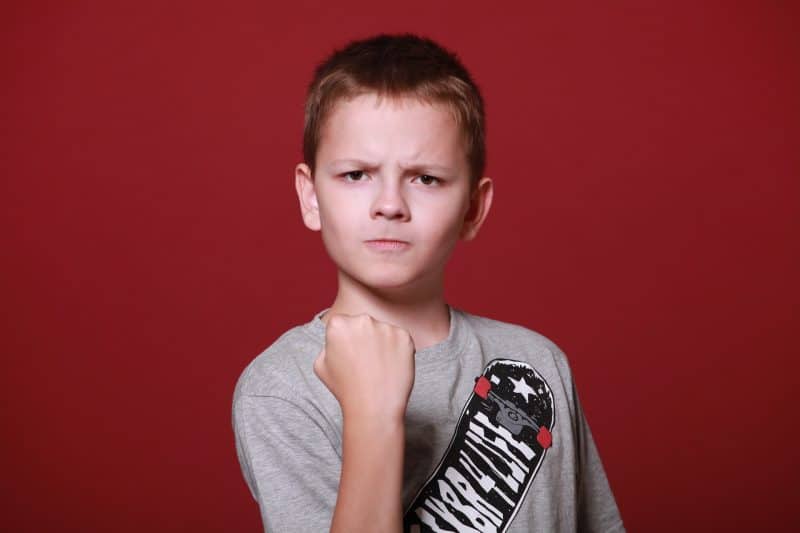 Niño con expresión de ira, levantando el puño cerrado