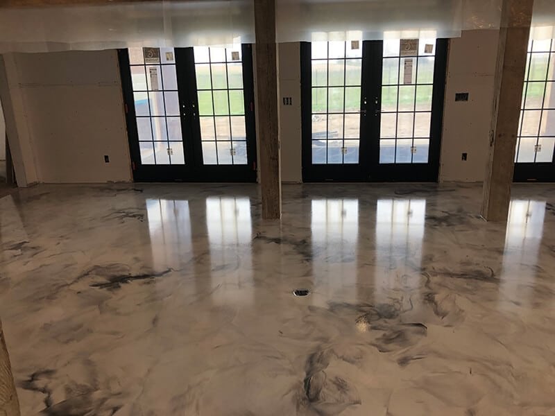 Polished marble-effect epoxy flooring in a modern room with large windows, installed by Minnesota concrete contractor.