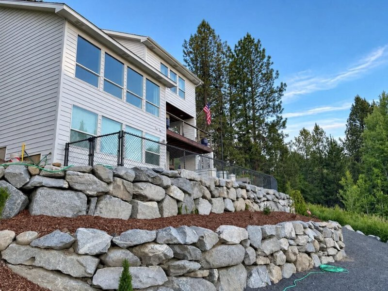Boulder retaining wall stepping down beside a home in Hillsboro, Oregon