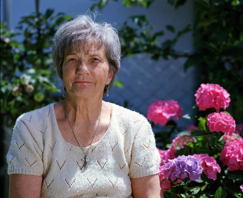 Señora mayor junto a hortensias