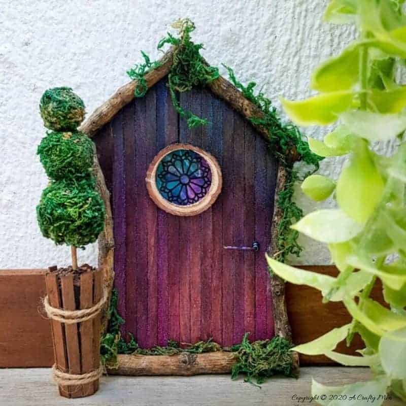Welcome the fae folk into your home with this gorgeous stained glass fairy door. Made with things you probably already have in your craft cupboard the door doubles up as a night light. #FairydoorDIY #FairyDoorIdeas #ACraftyMix #MakeAFairyDoor #MiniatureStainedGlass #AlcoholInk