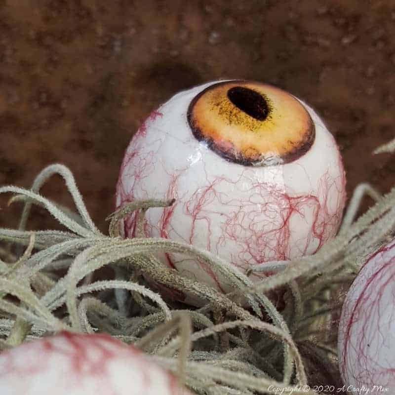 Up the creepy stakes this Halloween and make these realistic eyeballs. Quick and budget-friendly they'll add just the right spooky factor to your decor. The tutorial includes free "iris" printables to use #HalloweenDecor #CreepyEyeballs #ACraftyMix #FreePrintables
