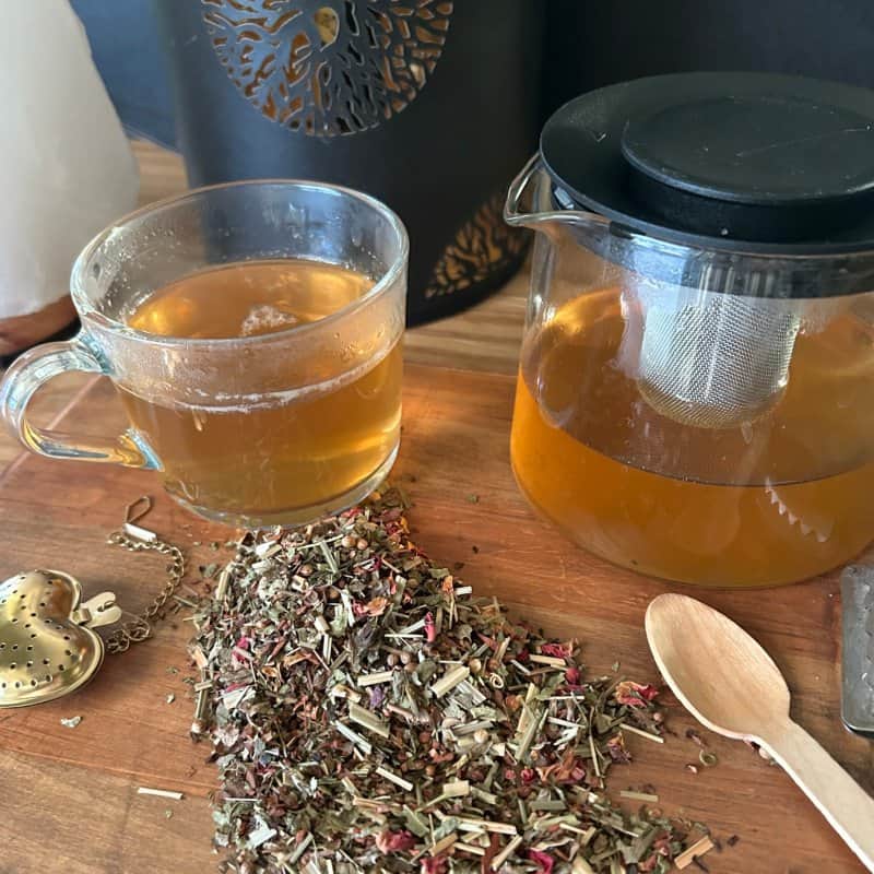 Herbal tea in glass mug with loose botanical tea blends.
