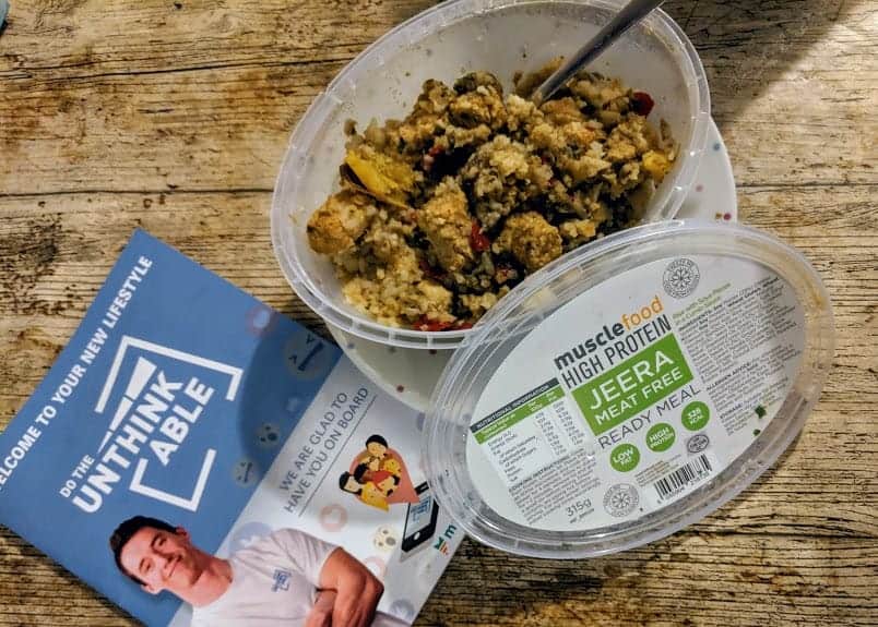 Jeera meat free musclefood meal with rice in a pot with fork in on a wooden table with DTU booklet
