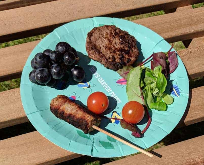 A blue paper plate with BBQ food on it