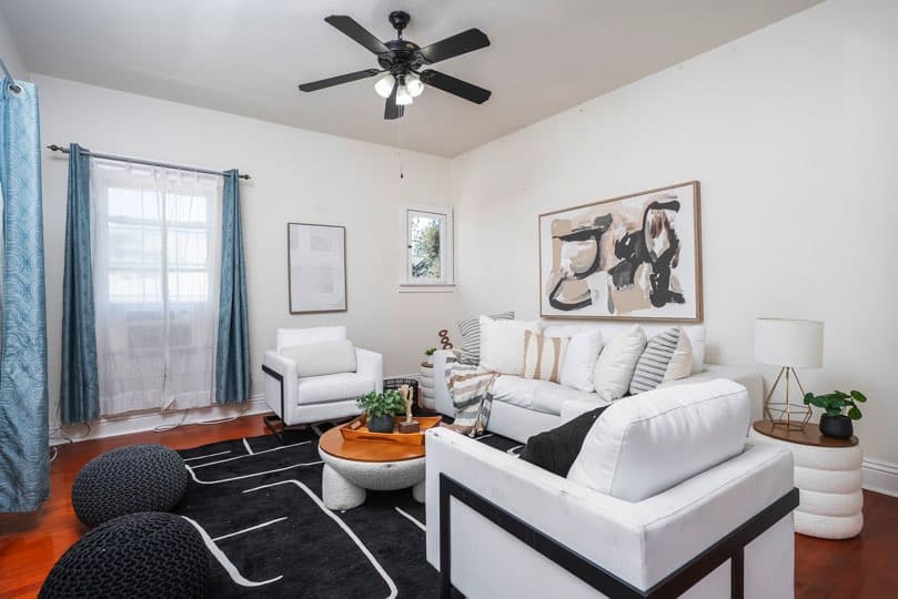 A living room features white seating, a round coffee table, and a black-and-white patterned rug on hardwood floors at 1932 C Street in Golden Hill.