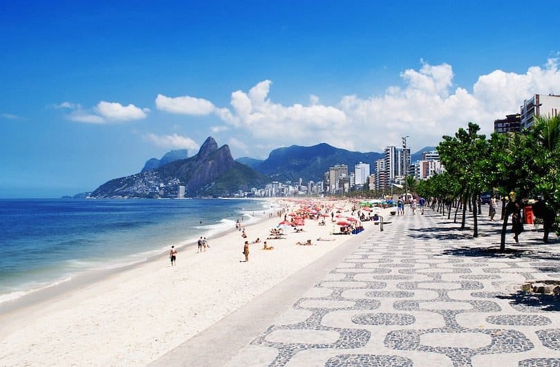 Busy Copacabana beach in Brazil with mountains and buildings in the background