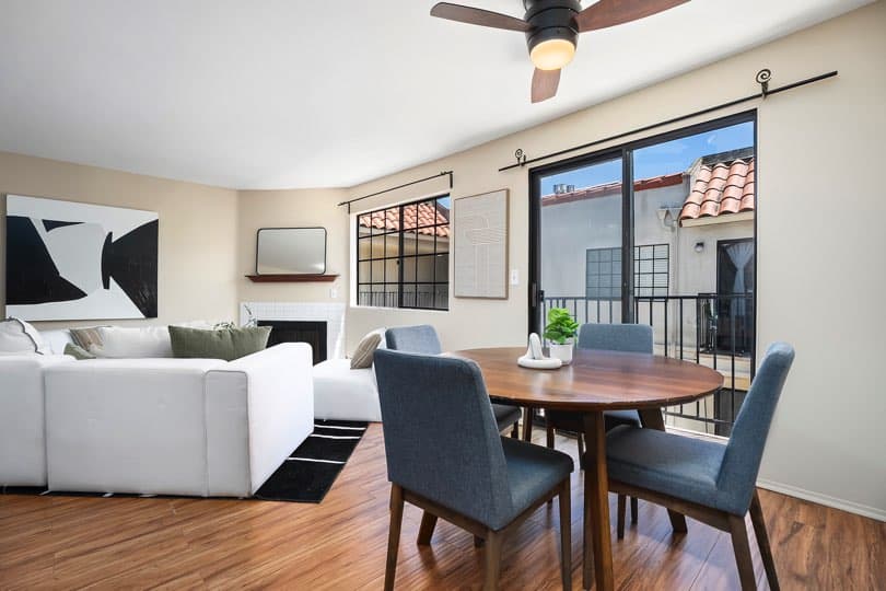 Dining area featuring a round wooden table and blue upholstered chairs next to a sliding glass door leading to a balcony at 205 Ohio St Unit 304 in North Park.