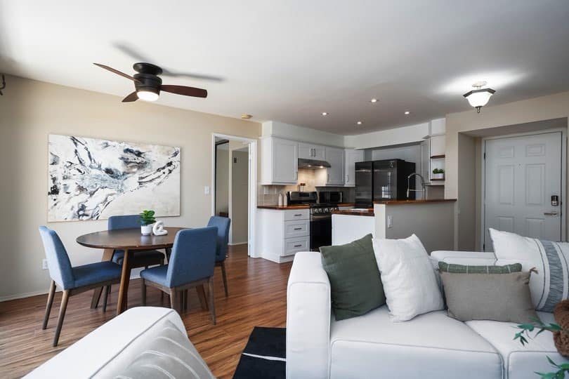 Living room area featuring wood-look floors, a white sectional sofa, a fireplace with a dark mantel, and open access to the kitchen at 205 Ohio St Unit 304 in North Park.
