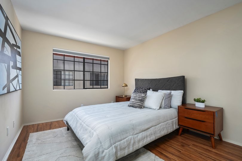 Bedroom with a dark gray upholstered headboard, wooden nightstands, wood-look floors, and a grid-style window at 205 Ohio St Unit 304 in North Park.