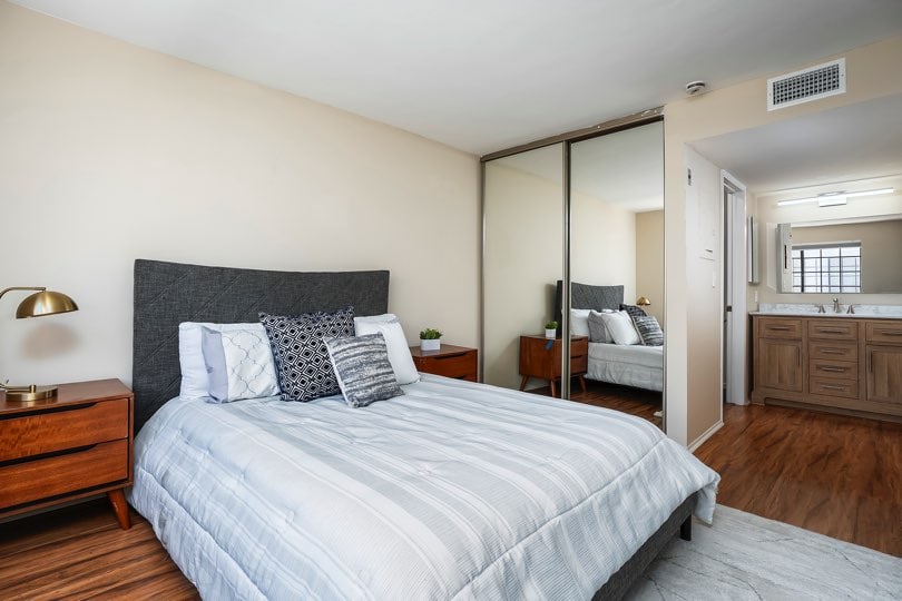 Bedroom with a dark grey headboard, a large sliding mirrored closet door, and a clear view into an attached bathroom vanity area at 205 Ohio St Unit 304 in North Park.