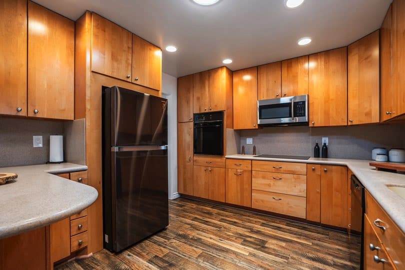 Kitchen featuring light wood cabinetry, stone-colored countertops, dark wood flooring, and a black refrigerator at 5237 Diane Ave in Clairemont.