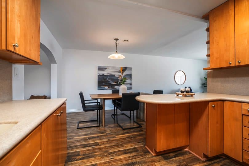Dining area featuring a wooden table with black chairs, dark wood flooring, and a view into an arched entryway at 5237 Diane Ave in Clairemont.