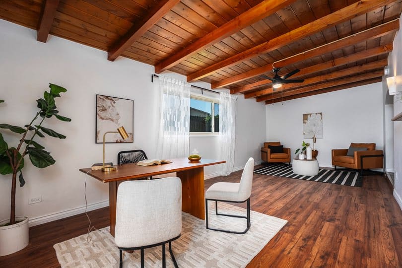 Dining area featuring a wooden table with black chairs, dark wood flooring, and a view into an arched entryway at 5237 Diane Ave in Clairemont.