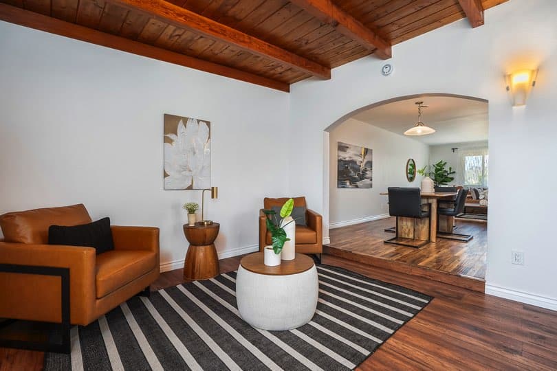 Sitting area with two tan leather armchairs, a round coffee table, and a wooden beamed ceiling opening into a dining room at 5237 Diane Ave in Clairemont.