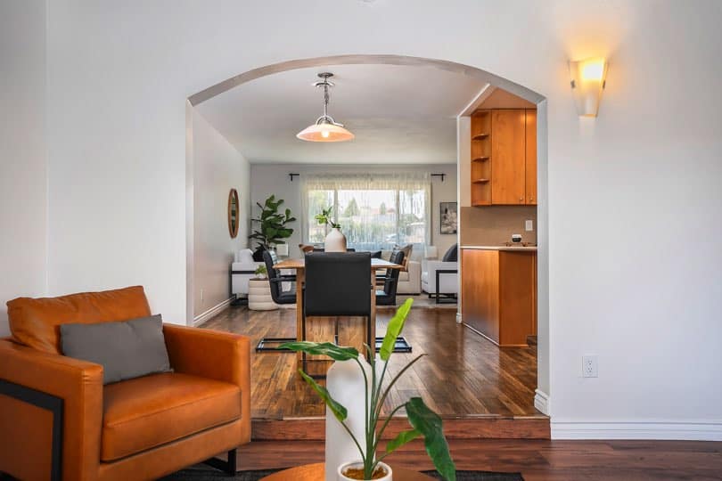 Tan leather armchair positioned in front of an arched entryway leading to the dining room and kitchen at 5237 Diane Ave in Clairemont.